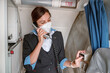 © Kostiantyn - Woman stewardess in face mask talking on telephone in airplane