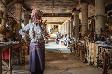 Old Burmese lady smoking a cigar at traditional market in Indein Village, Shan State, Myanmar (Burma).