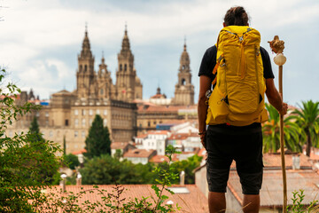 pilgrim looking at the cathedral of Santiago de Compostela in Spaink, backpack on his back.