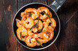 Fried with butter and garlic prawns shrimps in a skillet. Wooden background. Top view