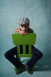 młody chłopak w czapce siedzi na zielonym krześle