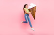 Profile photo of crazy hungry lady hold big cone ice cream jump lick wear green top jeans isolated pink color background