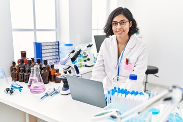 Canvas Print - Young latin woman wearing scientist uniform using laptop working at laboratory