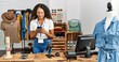 © Krakenimages.com - Young latin shopkeeper woman using smartphone working at clothing store.