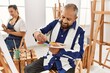 © Krakenimages.com - Young artist woman and senior painter man at art studio classroom painting on canvas with brush and oil painting
