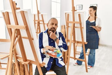 Poster - Senior artist man at art studio looking confident at the camera smiling with crossed arms and hand raised on chin. thinking positive.