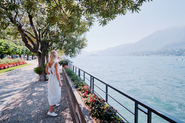 Wall Mural - Travel by Italy. Young woman walking on the promenade of Como Lake.