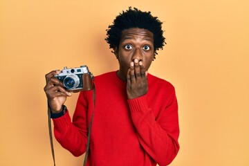 Sticker - Young african american man holding vintage camera covering mouth with hand, shocked and afraid for mistake. surprised expression