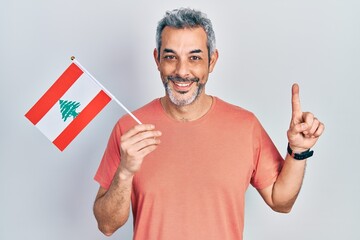 Poster - Handsome middle age man with grey hair holding lebanon flag smiling with an idea or question pointing finger with happy face, number one