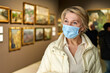 © JENOCHE - woman visitor wearing an antivirus mask in museum looking at pictures