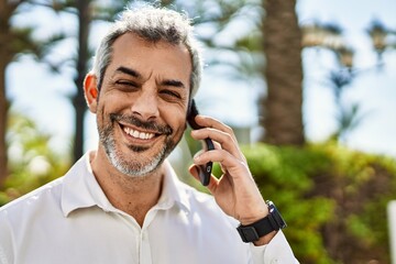 Middle age grey-haired man smiling happy talking on the smartphone at the city.