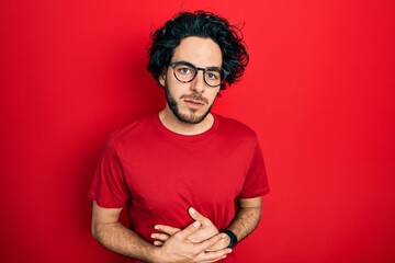 Sticker - Handsome hispanic man wearing casual t shirt and glasses with hand on stomach because indigestion, painful illness feeling unwell. ache concept.