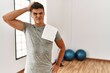 © Krakenimages.com - Young hispanic man wearing sportswear and towel at the gym confuse and wonder about question. uncertain with doubt, thinking with hand on head. pensive concept.