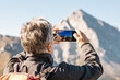 © ADDICTIVE STOCK - Senior traveling woman taking photo on mountains