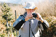 © ADDICTIVE STOCK - Senior traveler taking photo during trekking