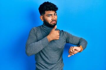 Wall Mural - Arab man with beard wearing turtleneck sweater doing thumbs up and down, disagreement and agreement expression. crazy conflict