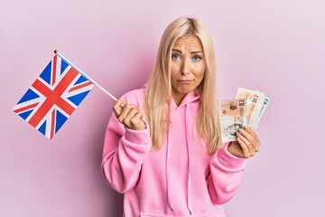 Wall Mural - Young blonde woman holding united kingdom flag skeptic and nervous, frowning upset because of problem. negative person.