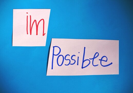 Card with the text impossible, cutting the word im so it written possible. success and challenge concept.