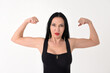 Portrait of a beautiful brunette woman in a bodybuilding pose showing muscles on a white background