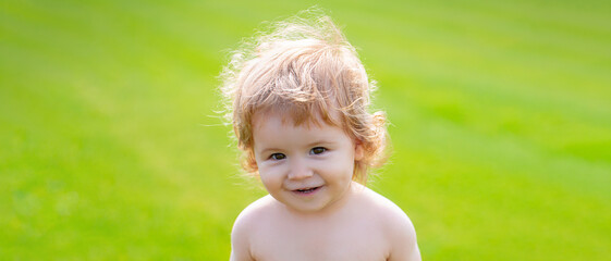 Banner with spring child face. Little baby in diaper playing in nature on the green grass. Baby and summer sunny weather. Blonde kid, laughing emotion, happy smiling face.