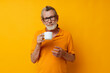 © Tatiana - Senior grey-haired man in a yellow t-shirt white mug isolated background