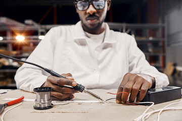 Wall Mural - african engineer using soldering iron at factory