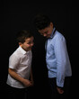 © Сергей Везнер - Two boys on a black background are brothers.Senior and junior.Atelier.they look at the floor.hands in pockets