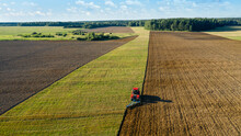 Scenic View Of Working Tractor In The Field Agricultural Field On A Summer Farm In The Evening. Aerial Photography, Top View Drone Shot. Agricultural Area Of Moscow Region. Agrarian Land In Summertime