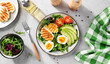 Healthy keto diet breakfast: boiled egg, avocado slices, grilled halloumi cheese, salad leaves. Light gray background. top view