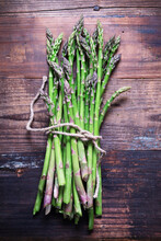 A Bunch Of Freshly Picked Asparagus Tied With String On A Wooden Background.