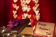 Happy Valentine's day writing on card with open gift box on heart shaped bokeh lights background