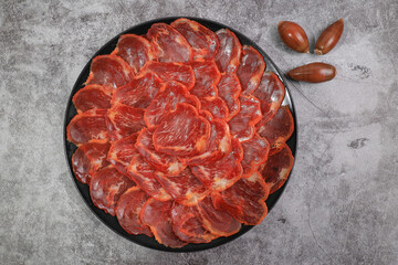 Portion of 100% acorn-fed Iberian chorizo from Extremadura decorated with acorns with dark gray background