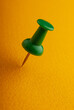 © APHOTOSTUDIO - Green vinyl paper clip on yellow paper, close-up.