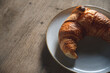 fresh golden brown croissant on a stoneware plate and rustic wooden table