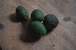 freshly harvested green avocados lying on a rustic wooden table