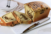 Sliced Loaf marble Cake on White Plate, Wooden Table.
