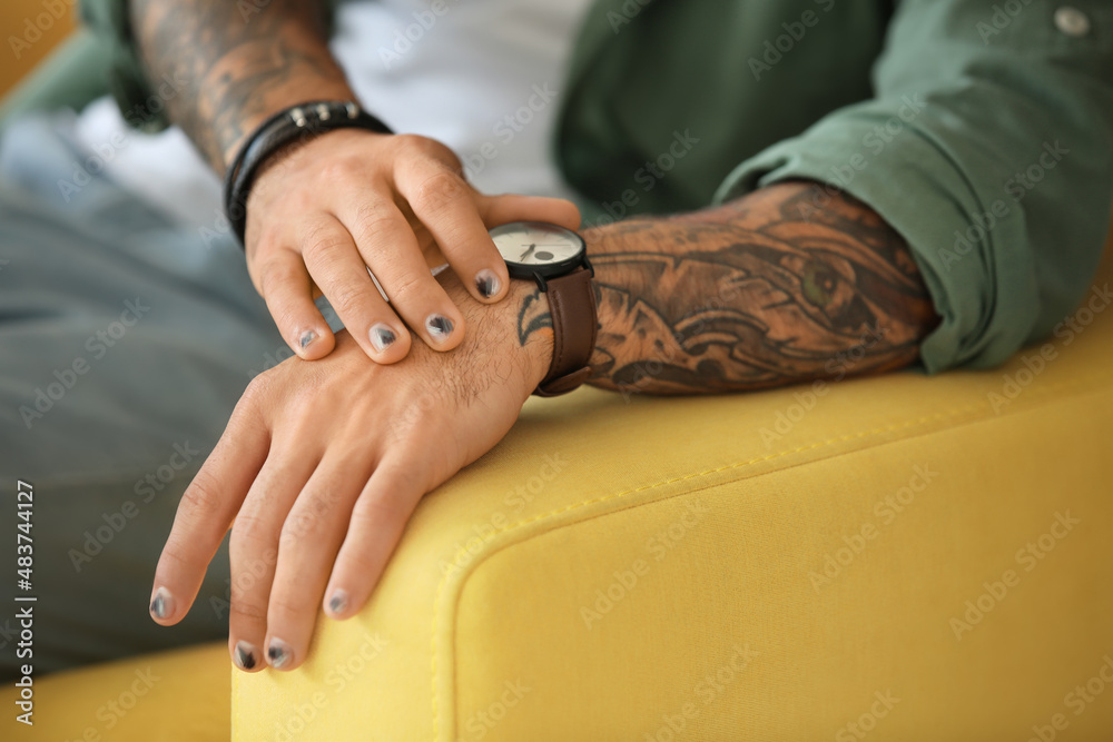 Male hands with stylish manicure on sofa armrest, closeup