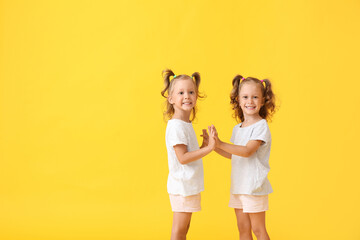 Poster - Cute little girls with ponytails holding hands on yellow background