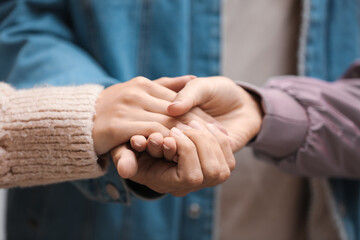 Wall Mural - Man and two beautiful women holding hands, closeup. Polyamory concept