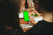 © Three Sixty Media/Wirestock - Ladies looking at the green screen of a smartphone at a dinner table