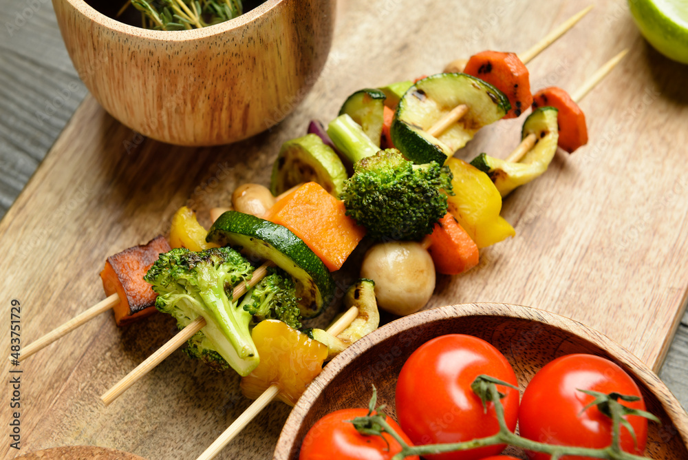 Board with tasty vegetable skewers on table, closeup