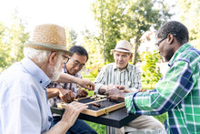 Group Of Senior Friends Playing Chess At The Park. Old Multiethnic Friends Making Activities Outdoor. Concept About Third Age And Lifestyle