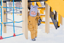 A Happy Baby 15-25 Months Old Is Playing On A Children's Playground In Winter