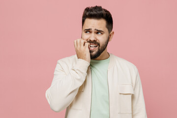 Sticker - Young puzzled mistaken confused sad caucasian man 20s wear trendy jacket shirt look aside biting nails fingers isolated on plain pastel light pink background studio portrait. People lifestyle concept.