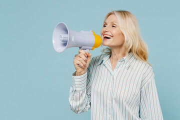 Wall Mural - Elderly smiling caucasian woman 50s wear striped shirt hold scream in megaphone announces discounts sale Hurry up isolated on plain pastel light blue color background studio. People lifestyle concept.