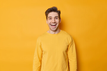 horizontal shot of happy young european man laughs joyfully expresses positive emotions dressed in c