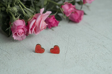 pink roses on a blurry background out of focus and two red hearts , the concept of Valentine's Day and March 8