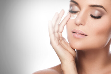 Wall Mural - beautiful woman applying moisturizing cream under her eye