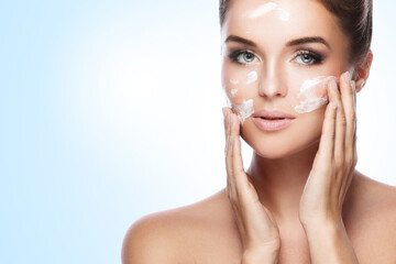 Wall Mural - beautiful woman applying moisturizing cream on her face