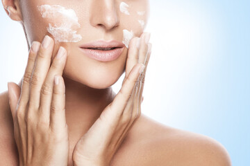 Wall Mural - beautiful woman applying moisturizing cream on her face